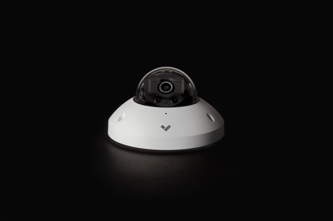 Verkada mini dome security camera shown in dramatic studio lighting against dark background.