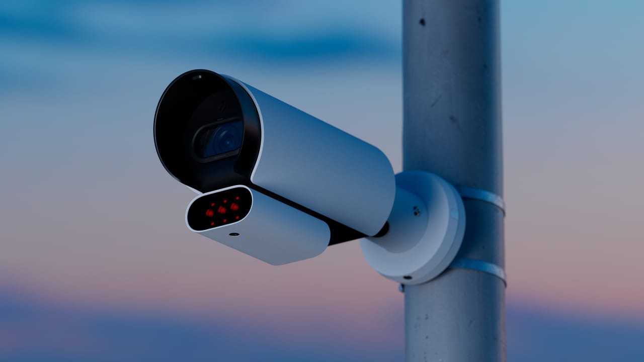 Verkada bullet security camera with IR LEDs mounted on a metal pole at dusk.