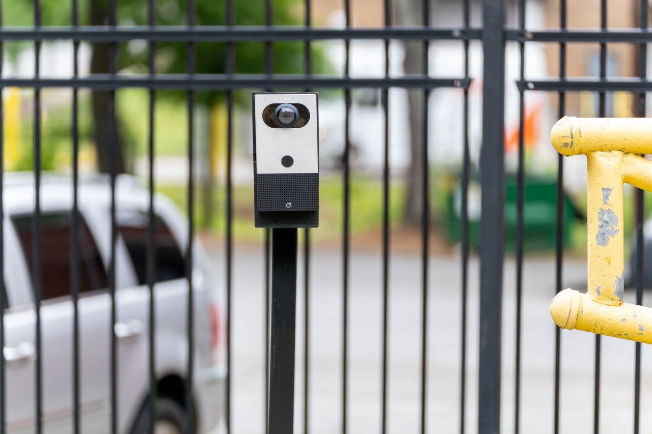 Verkada intercom device mounted on a black metal perimeter gate outdoors.