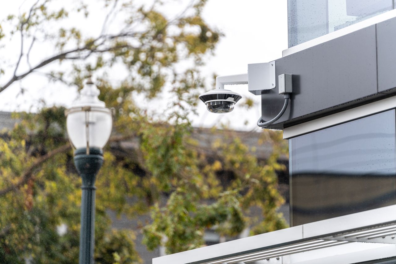 A Verkada multisensor dome camera mounted on a building exterior in rainy weather.