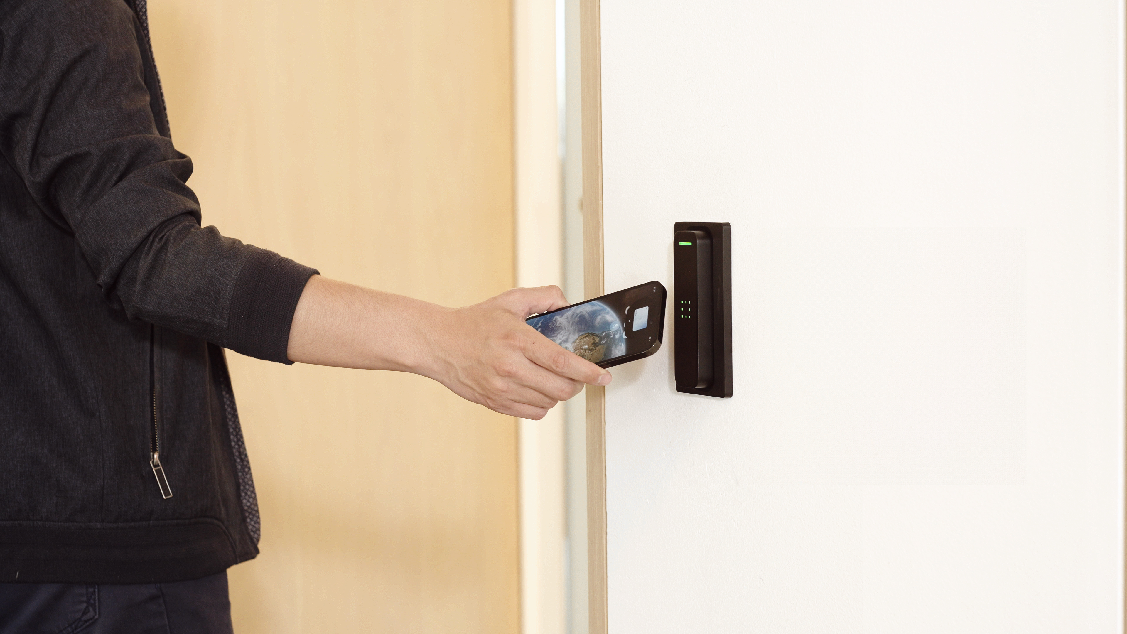Person holding a smartphone near a Verkada access control card reader on a white door.