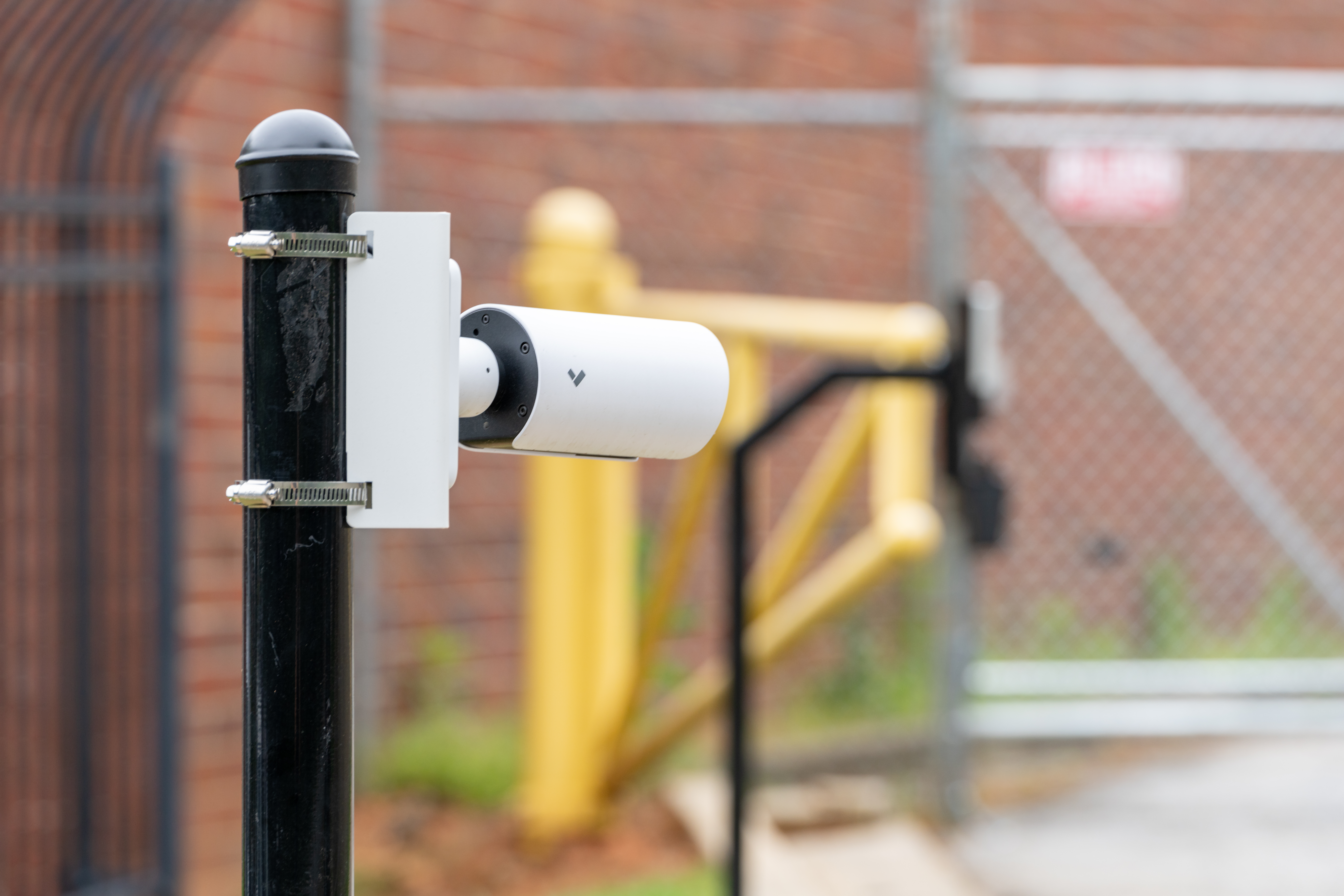 Verkada bullet camera mounted on a black pole at a building exterior perimeter.