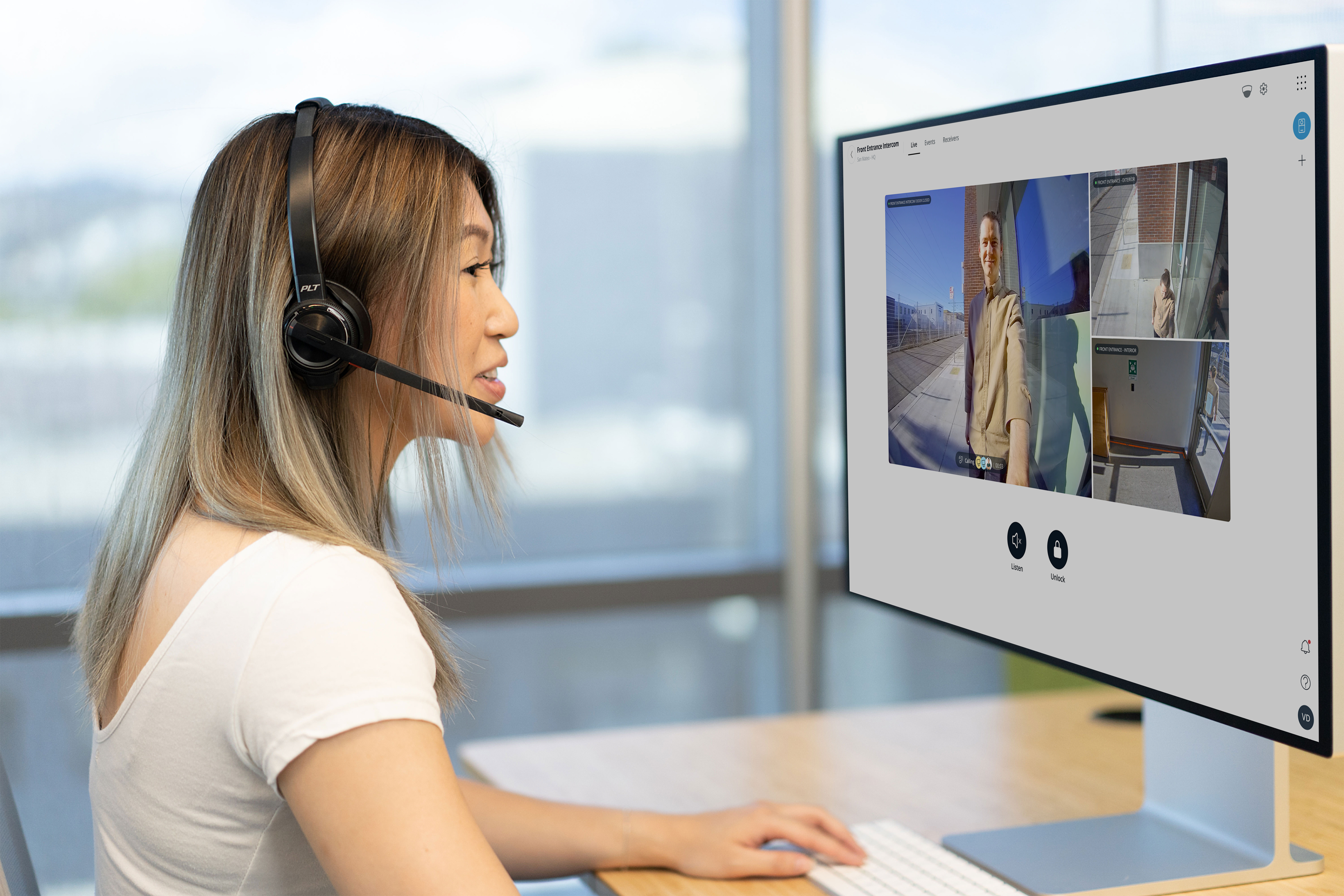 A receptionist wearing a headset answers a Verkada intercom call at her desk.