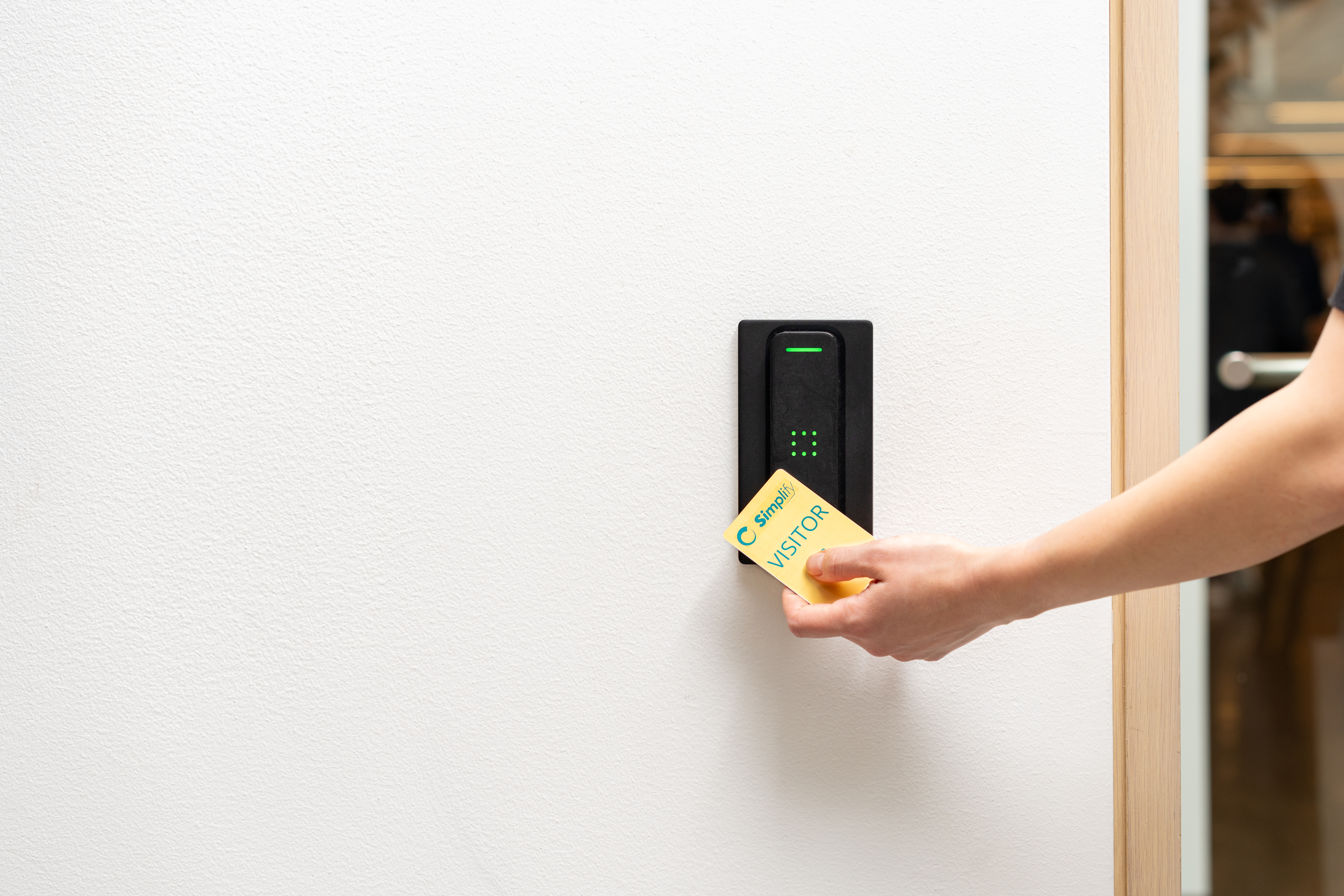 A person taps a Simpli visitor badge card on a Verkada access control reader.